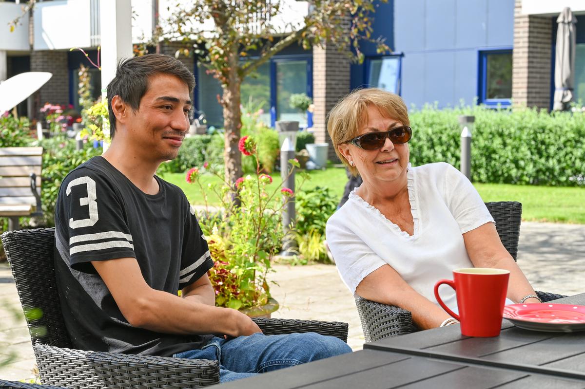 En yngre man och en äldre kvinna, boende på Sällbo på Fredriksdal, fikar utomhus